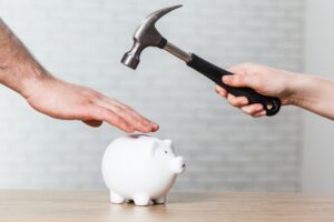 A hand holding a hammer which is raised above a white piggy bank